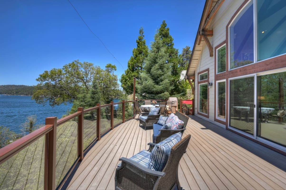 Wraparound lakeside deck with glass-rail views and outdoor seating