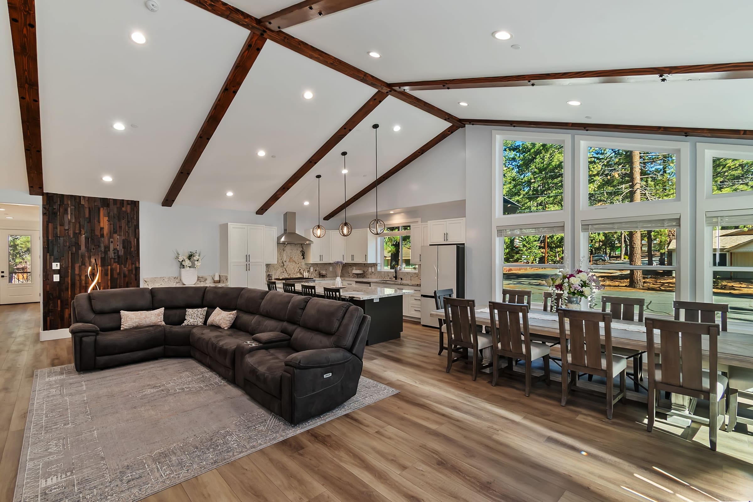 Vaulted wood-beam living space with wall-to-wall forest views