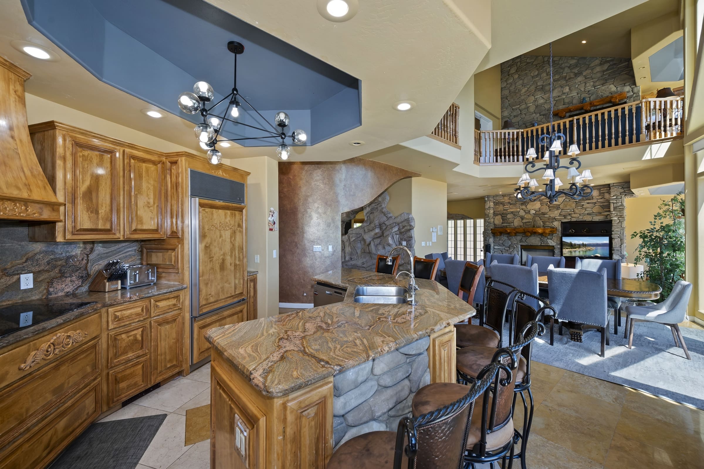 Two-story great room with dramatic stone fireplace and open kitchen