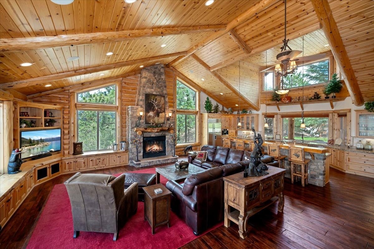 Vaulted log-beam great room with stone fireplace and open kitchen