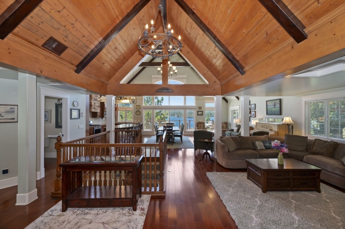 Vaulted wood-beam great room with lake views beyond