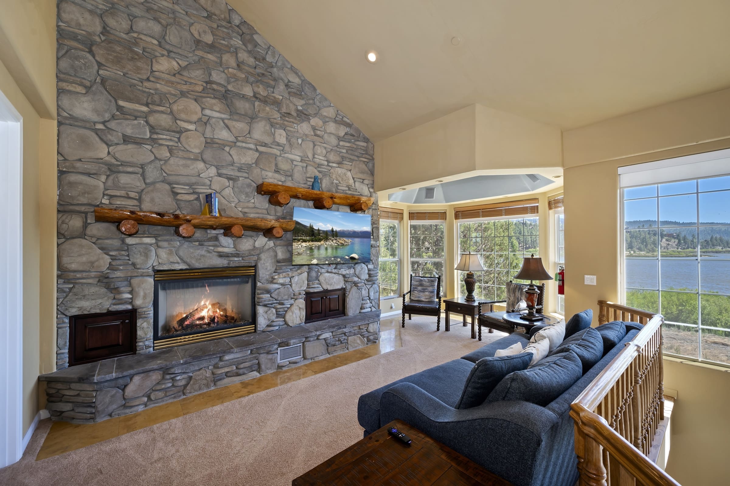 Floor-to-ceiling stone fireplace with lakefront bay window views