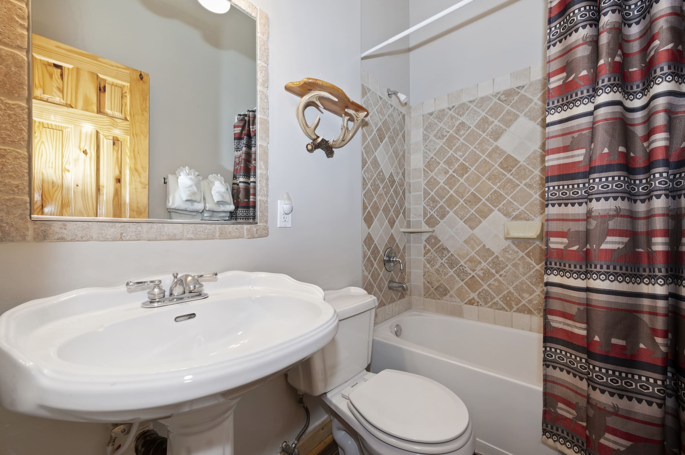 Rustic bath with pedestal sink and antler accent