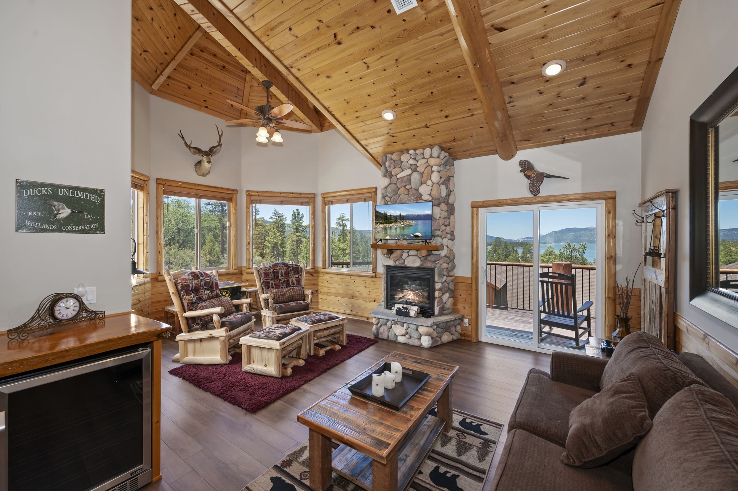 Vaulted-cedar living room with stone fireplace and lake views