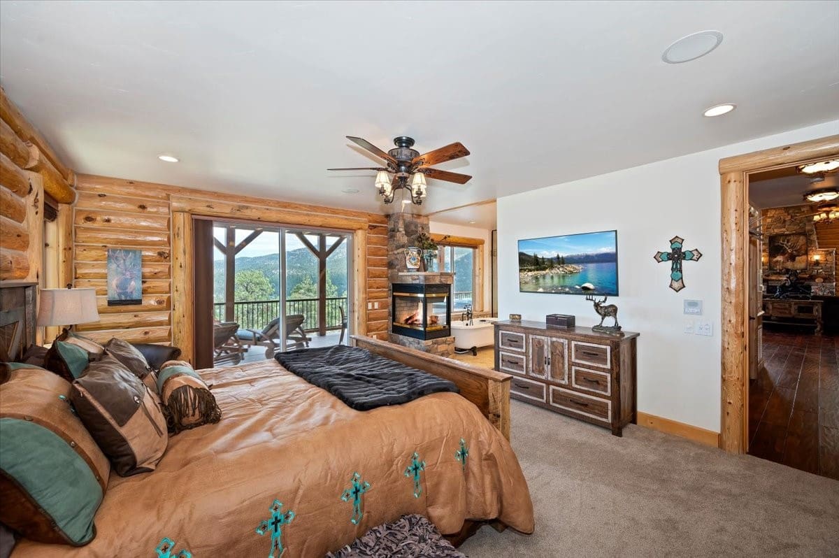Log-cabin primary suite with fireplace and mountain-view balcony