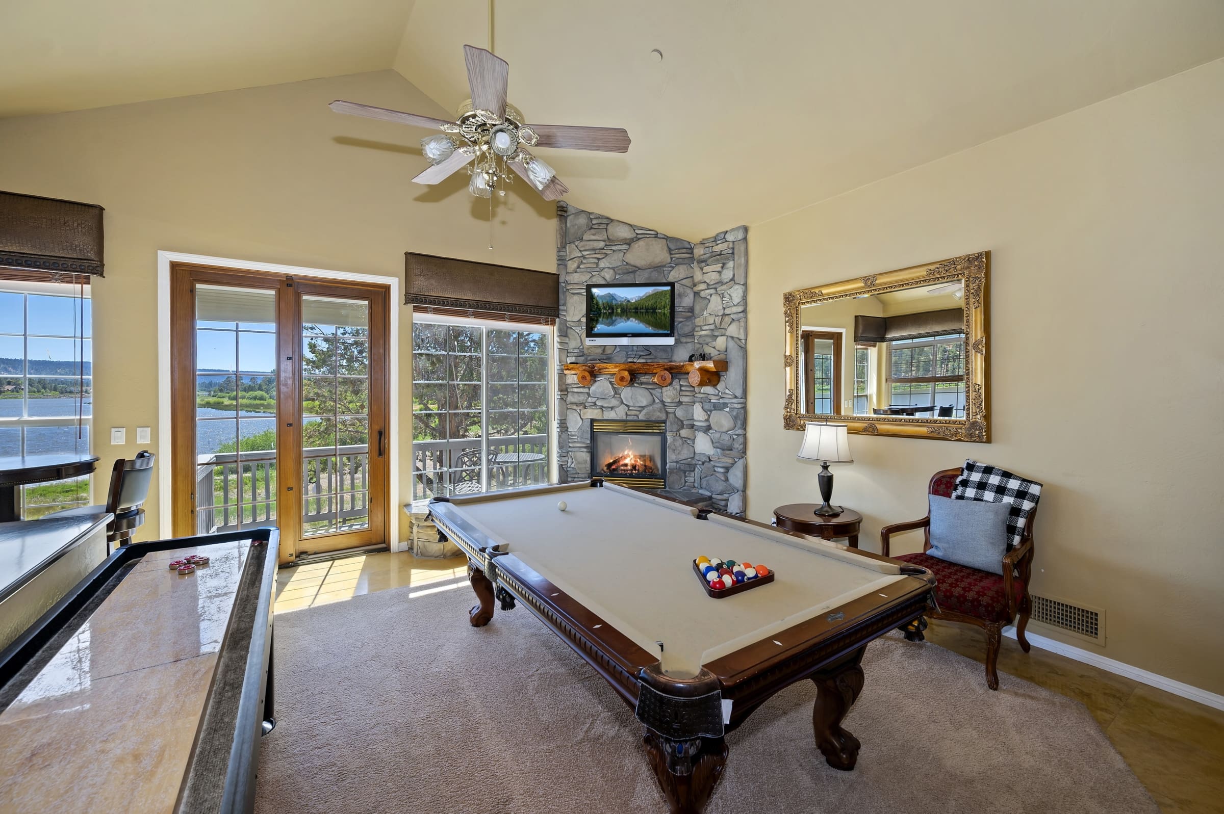 Game room with pool table, stone fireplace, and lake views