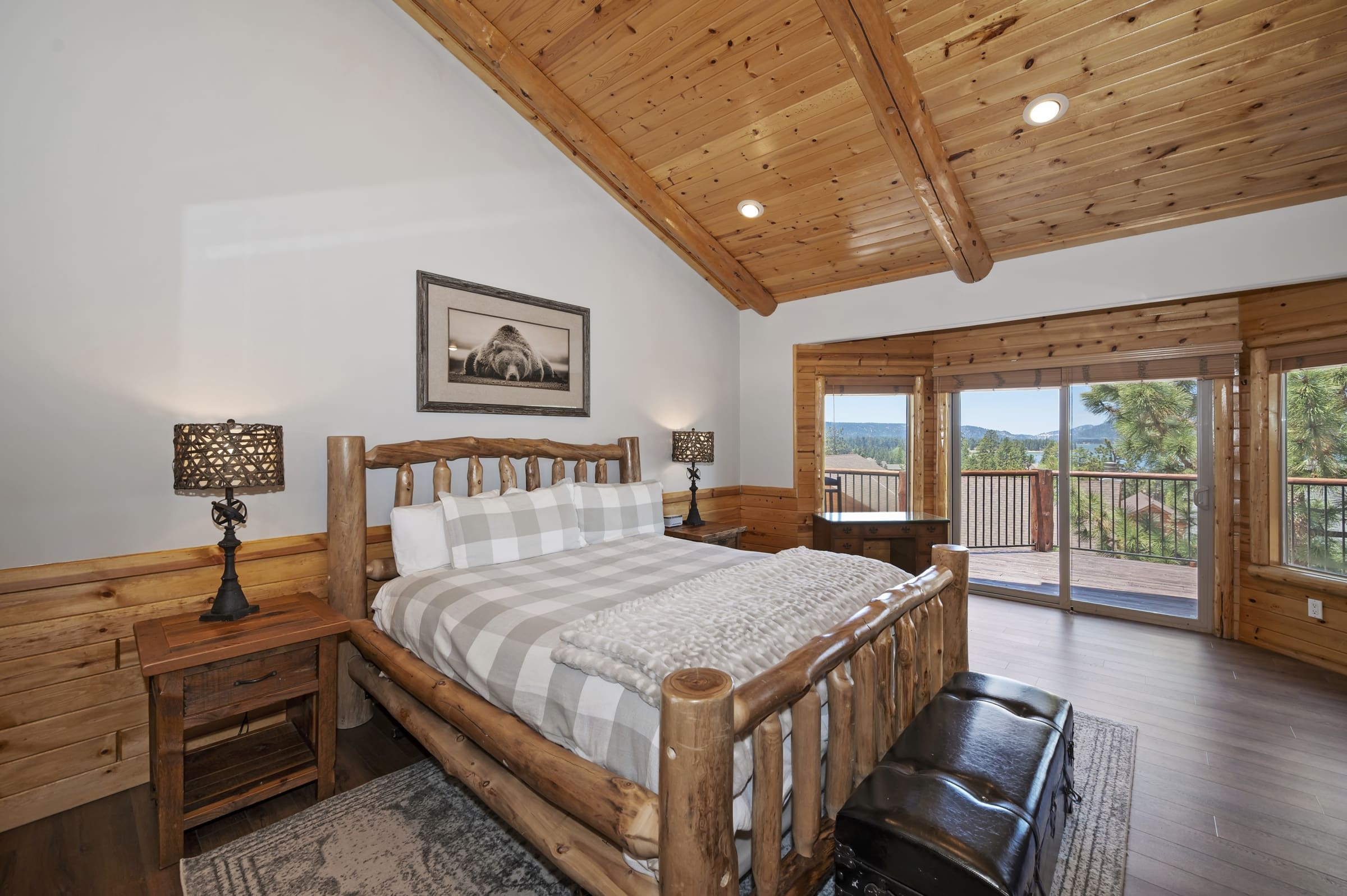 Log-framed primary suite with vaulted pine ceilings and private balcony views