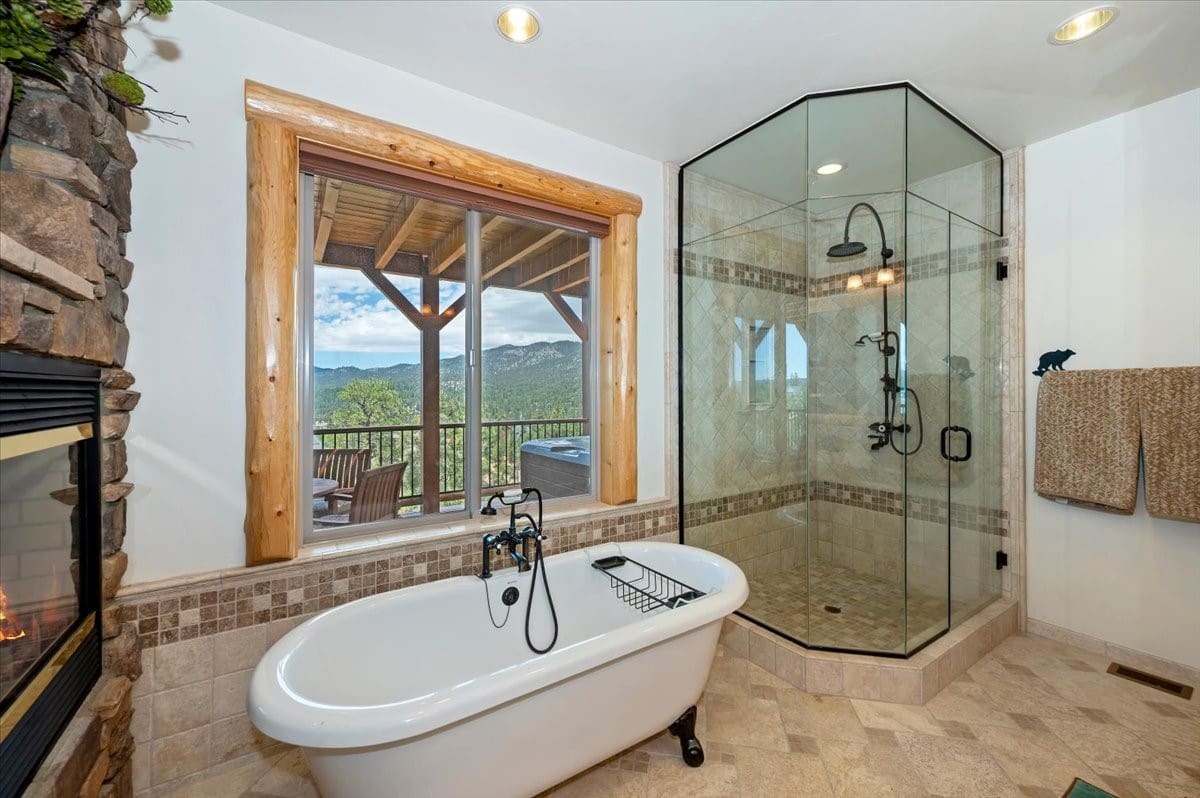 Soaking tub with fireplace and mountain-view window