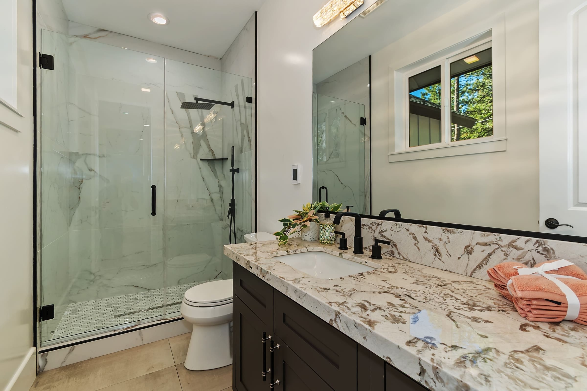 Marble-clad glass shower with matte black fixtures