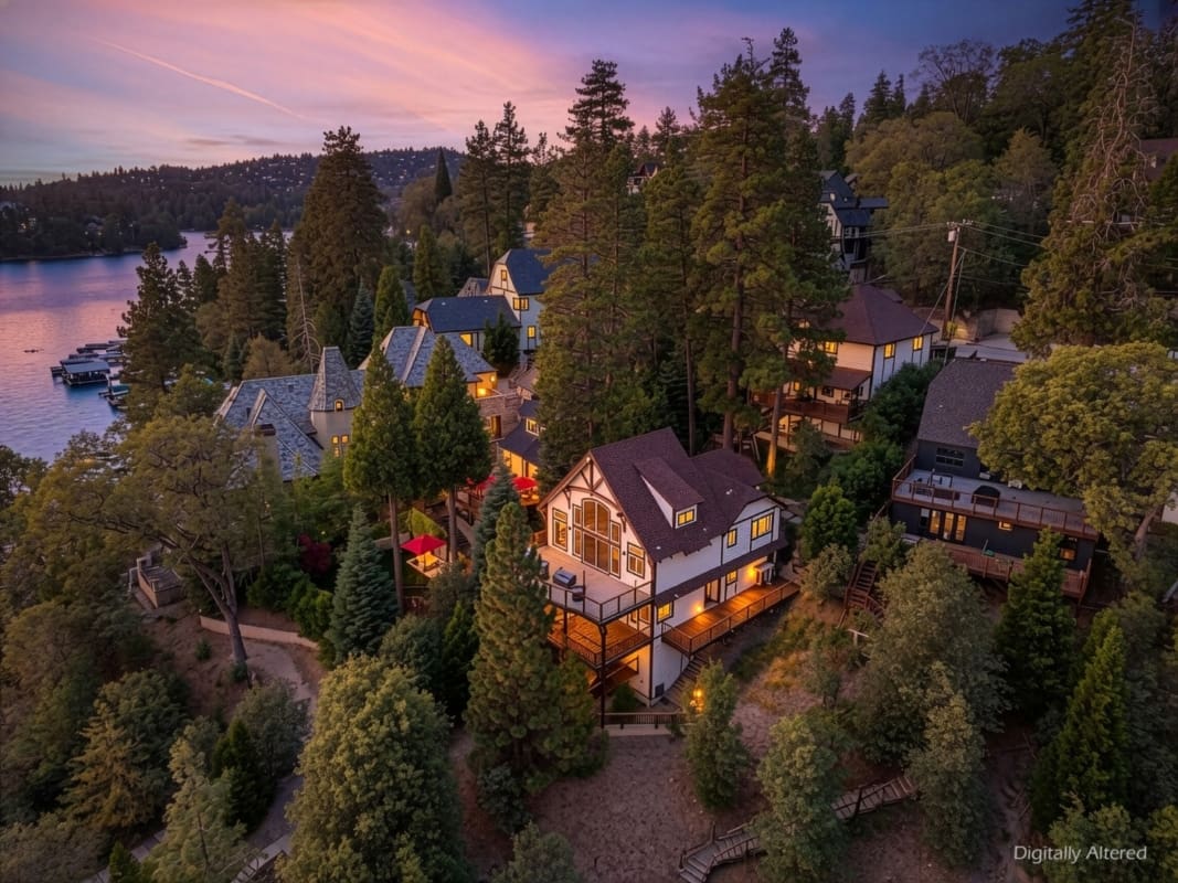Twilight aerial view of Tudor-style lakeside retreat among pines