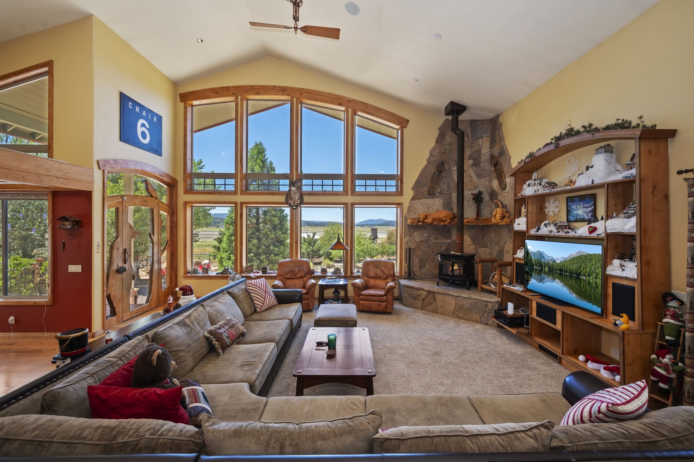 Vaulted living room with stone fireplace and mountain views