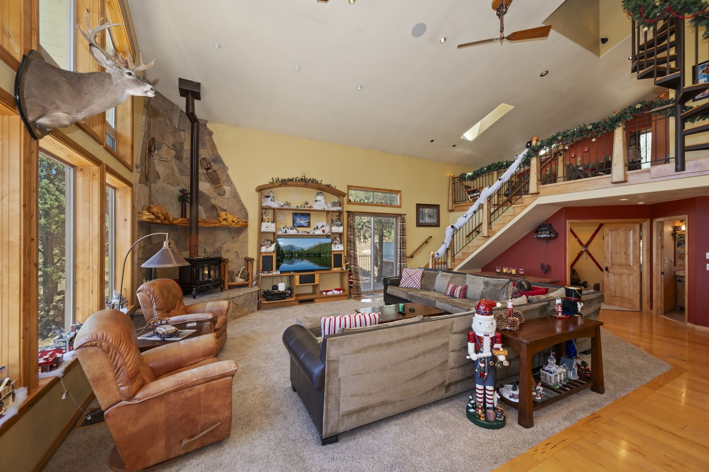 Vaulted great room with stone fireplace and loft staircase