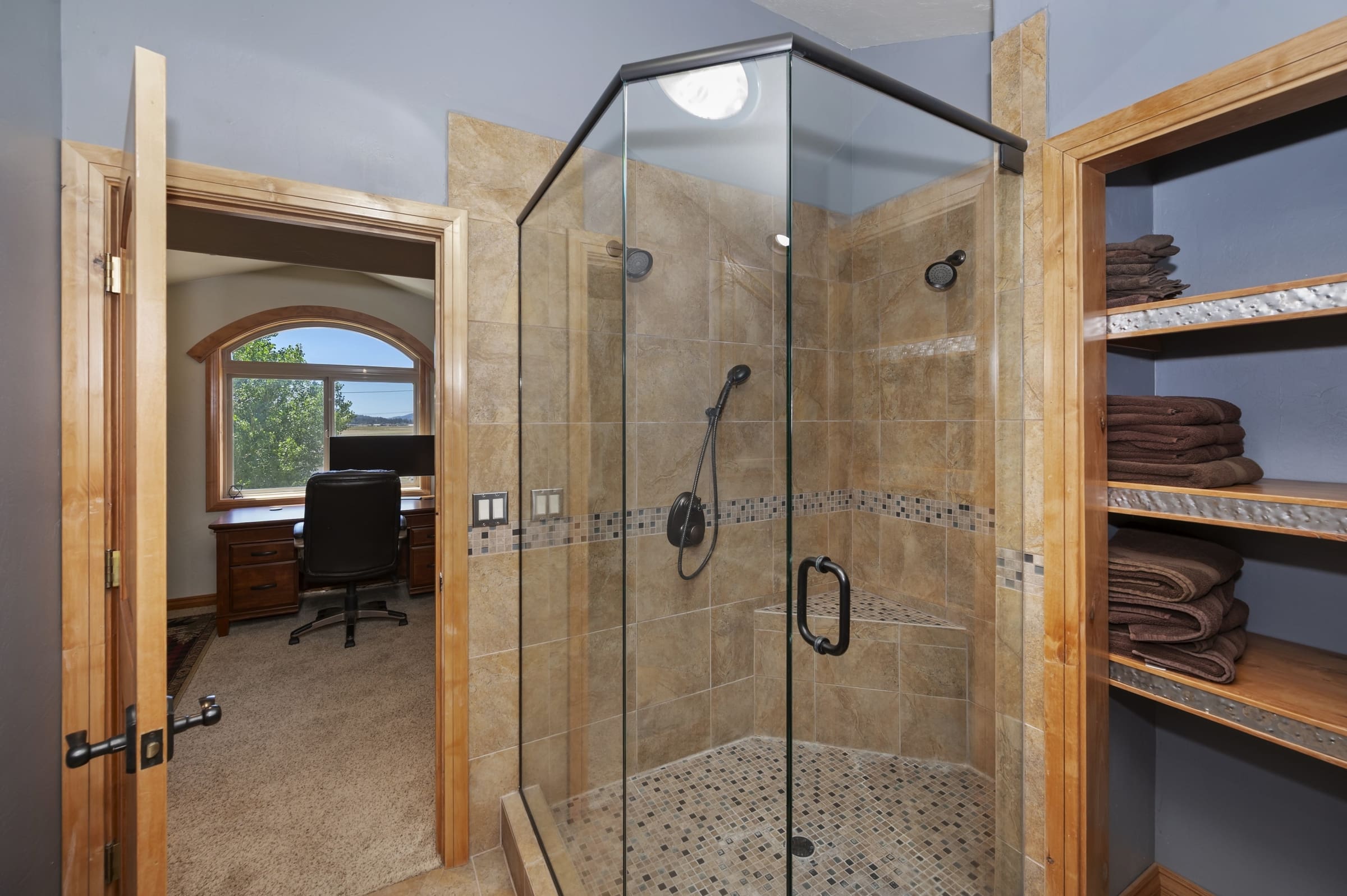 Frameless glass shower with tiled seat and built-in linen shelving