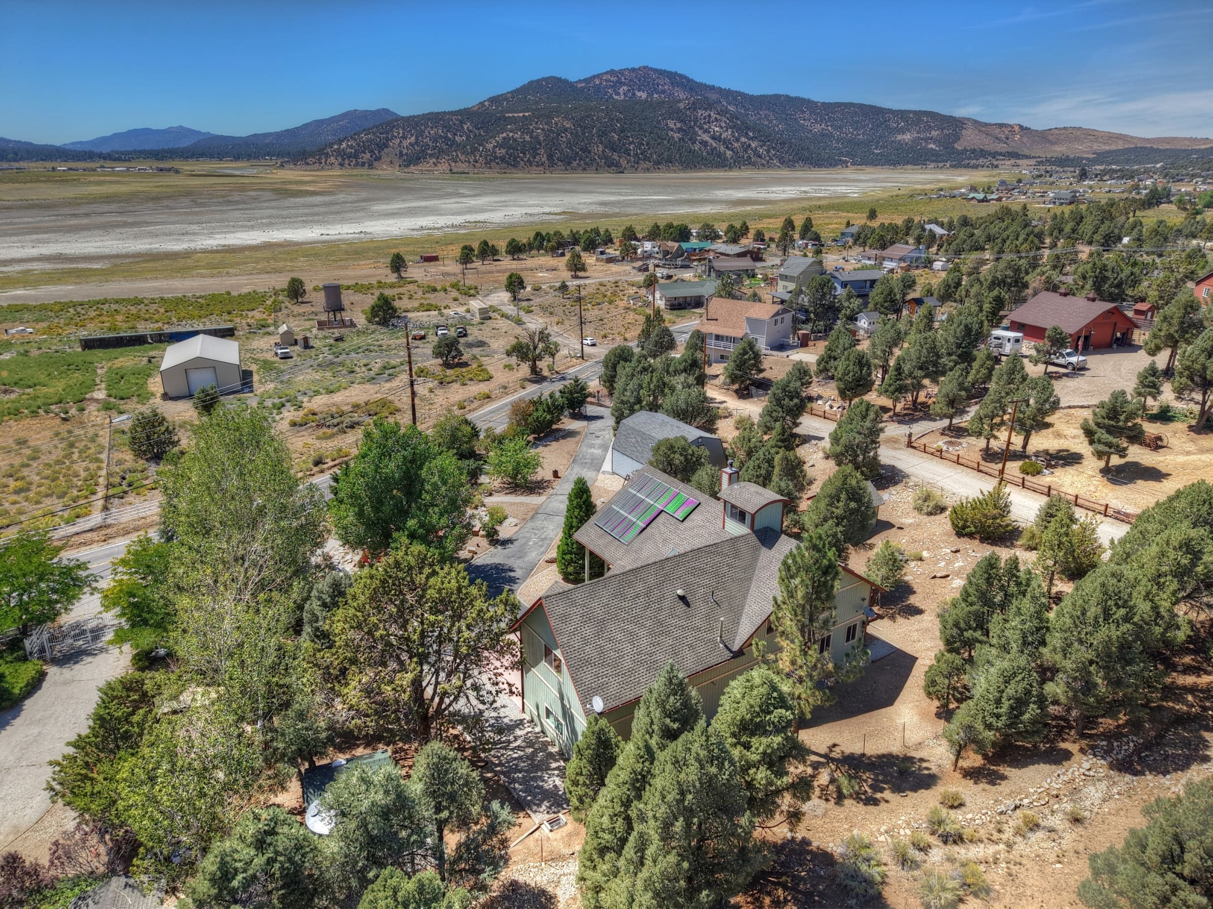 Aerial view with solar panels, pines, and mountain backdrop